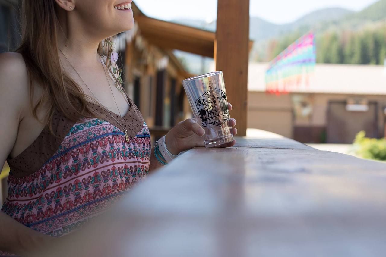 Happy young woman holding an empty beer glass outside of Old Schoolhouse Taproom