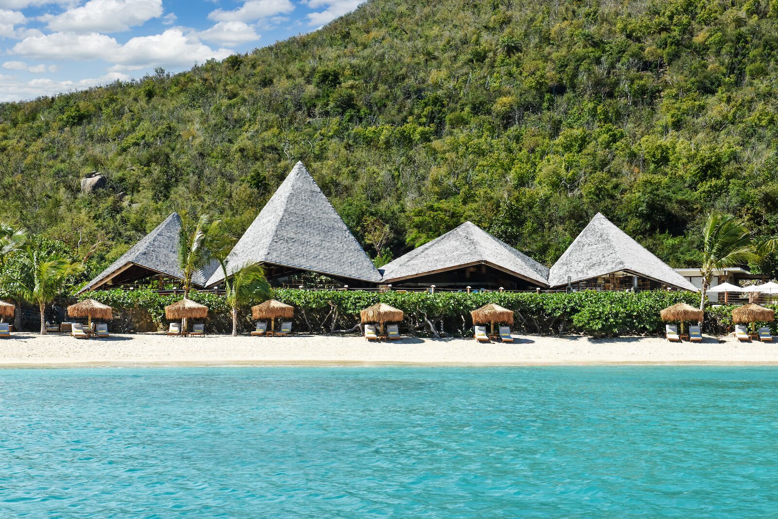 View of Rosewood Little Dix Bay beach with lounge chairs from the ocean